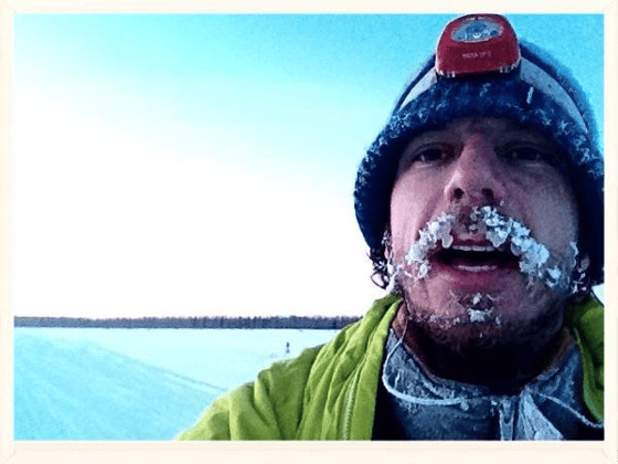 Pete Ripmaster takes a selfie with frosted beard and headlamp while traveling across an expanse of snow