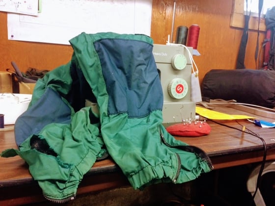blue and green NOLS windpants draped over a sewing machine