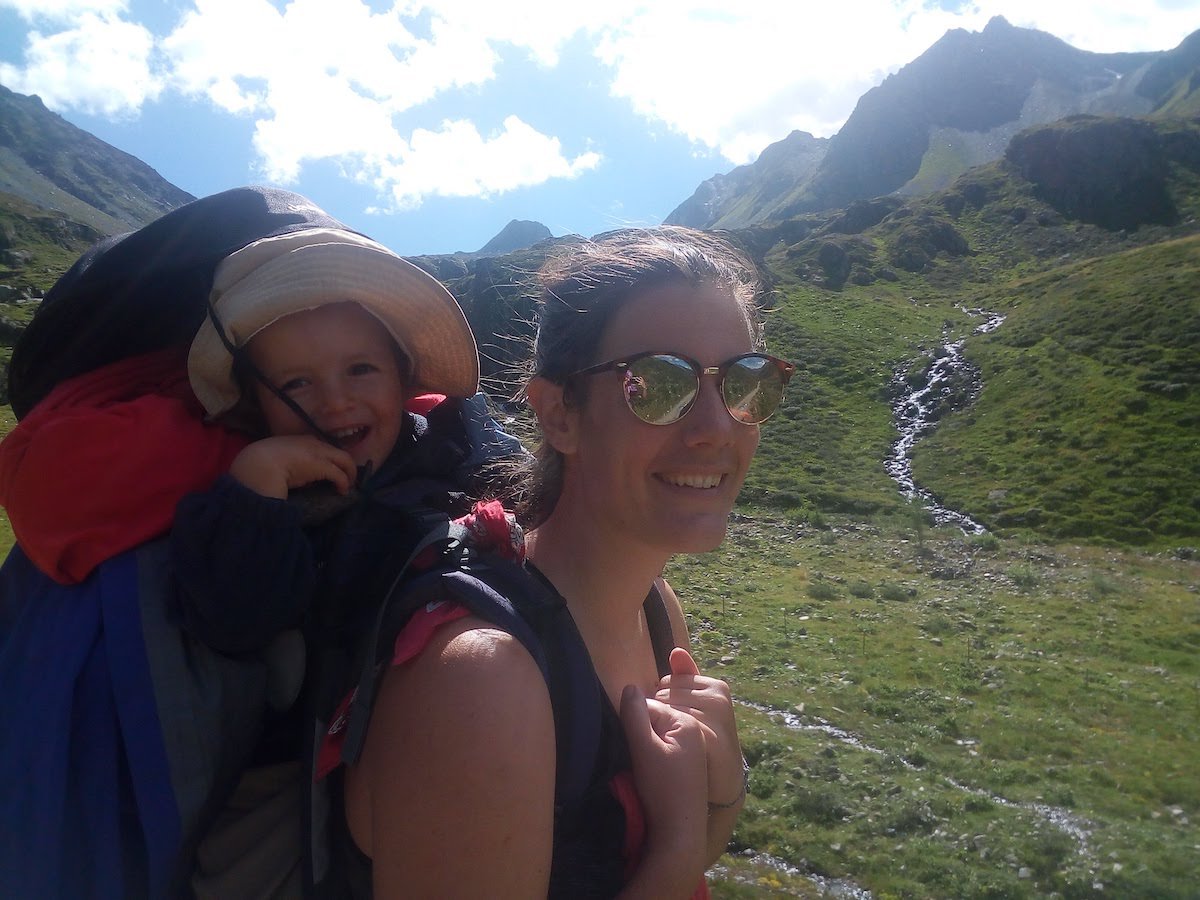 Woman carries a toddler in a backpack while hiking