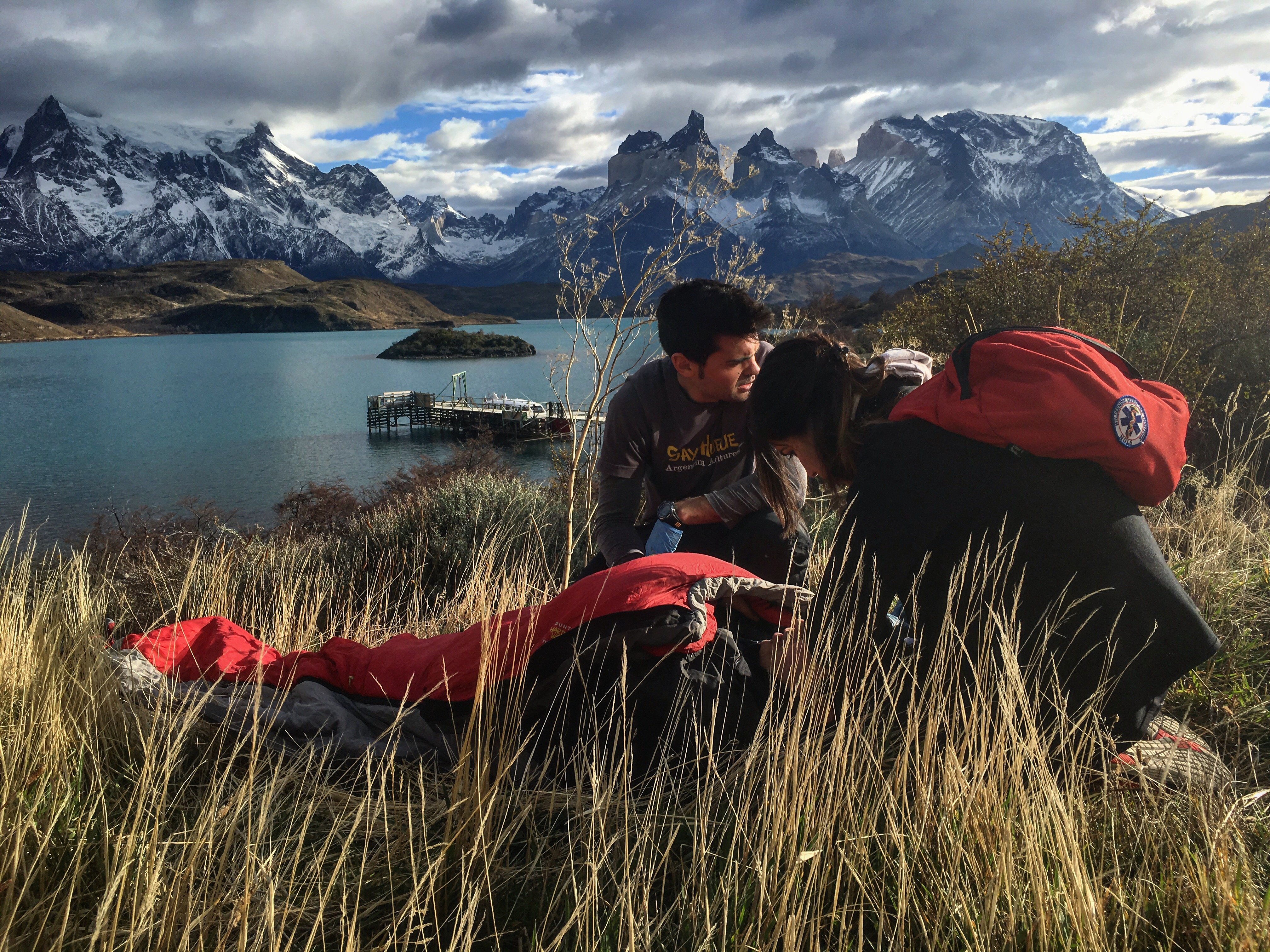 Man and man with backpack practice giving patient care with Torres del Paine mountains in Chile in the backgroujd