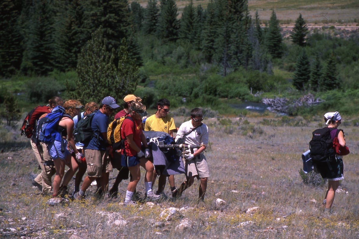 Archival photo from the 90s of a group carrying a litter in a rocky field