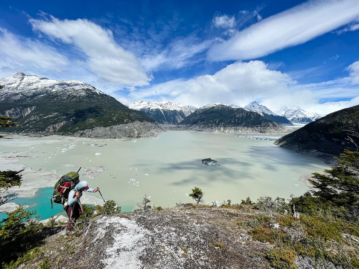 Woman hikes above a large mountain lake