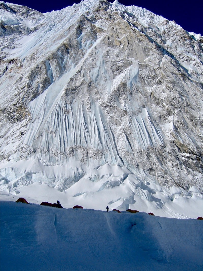 Outlines of tents in front of a huge icy mountain massif