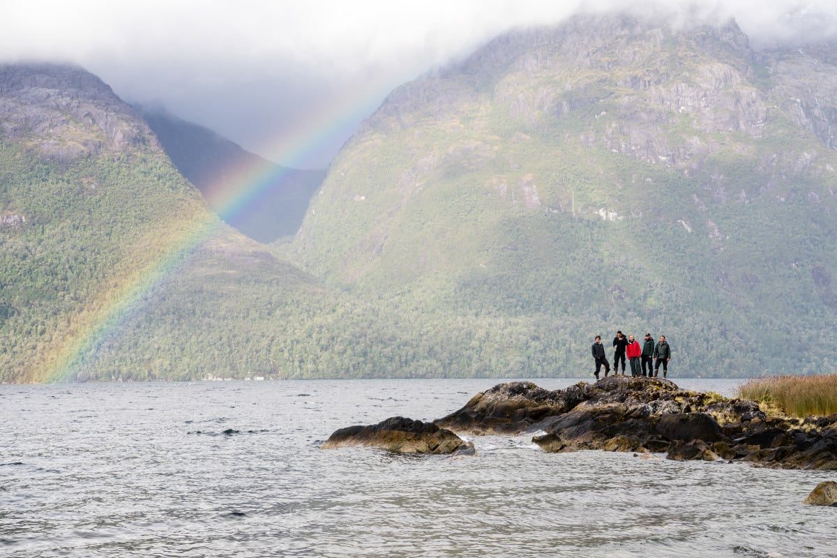 Rainbow stretches across the ocean observed by a group of NOLS students on shore