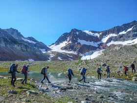 Naval Academy Mountaineering course participants cross a stream while backpacking. 