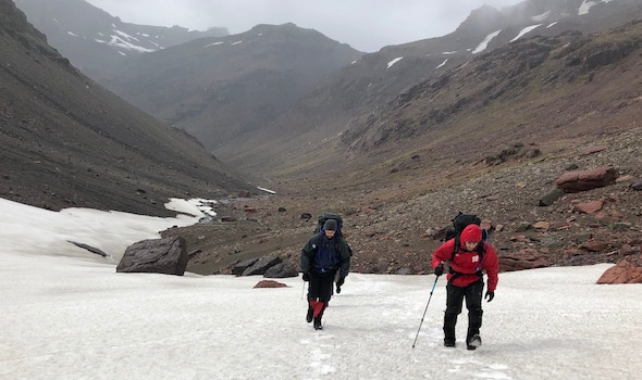 two Columbia MBA students on a NOLS course trek up a snowfield in Patagonia