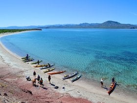kayaks beached on the shore beside turquoise water on a NOLS course in Baja
