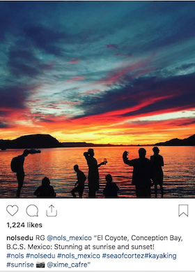 NOLS instagram post of spectacular sunrise over Conception Bay with figures silhouetted on the beach