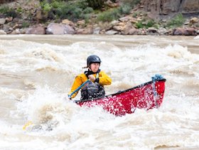 NOLS participant paddles whitewater kayak through a rapid