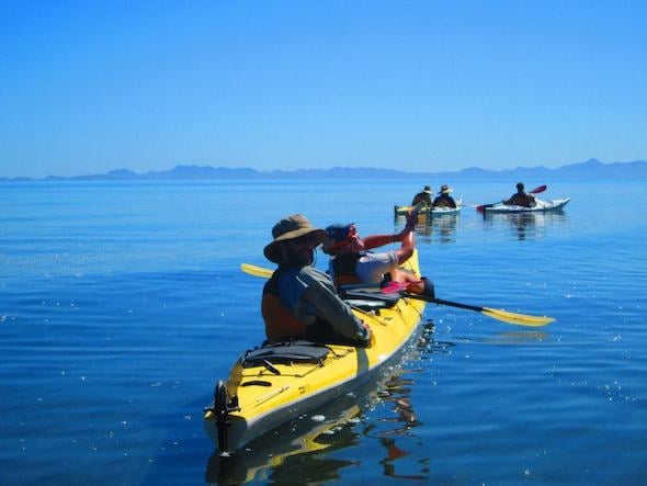 two NOLS participants in a double kayak paddling on calm water in Baja California