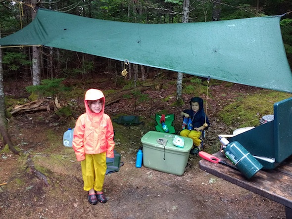 two children in camp with tarp strung up between trees