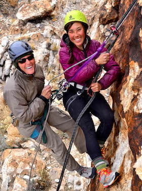 two smiling NOLS participants climbing