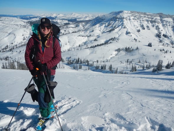 smiling NOLS student at the top of a slope on a backcountry skiing course