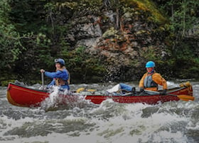 smiling NOLS students whitewater canoe in the Yukon