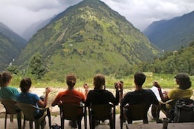 six NOLS students drink chai in India while looking toward the mountains