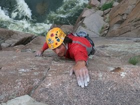 NOLS participant rock climbs with whitewater below