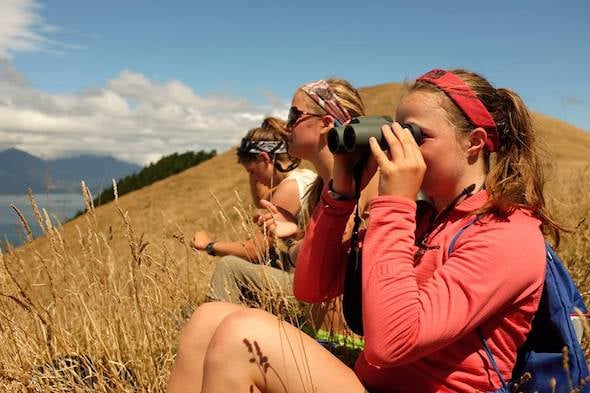 NOLS students look through binoculars on a semester in New Zealand