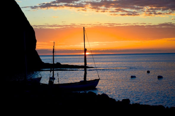 silhouetted Drascombe Longboat anchored near shore at sunset in Baja