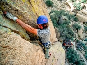 climber wearing blue helmet high on a rock face