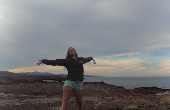 smiling NOLS student with outstretched arms on the Baja coast