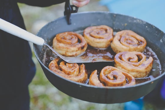 holding out a fry bake containing five cinnamon rolls