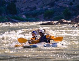 two NOLS participants paddle whitewater kayaks in the Rockies
