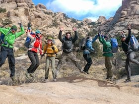 seven smiling NOLS students leap into the air while exploring the Southwest 