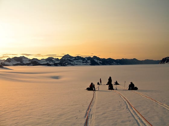 NOLS students on rope teams take a break on a snowfield in Alaska