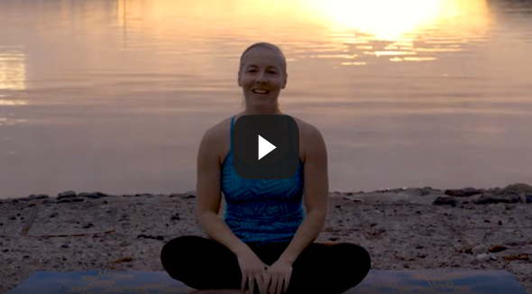 smiling female NOLS instructor sits on a yoga mat in the beach in Baja at sunrise