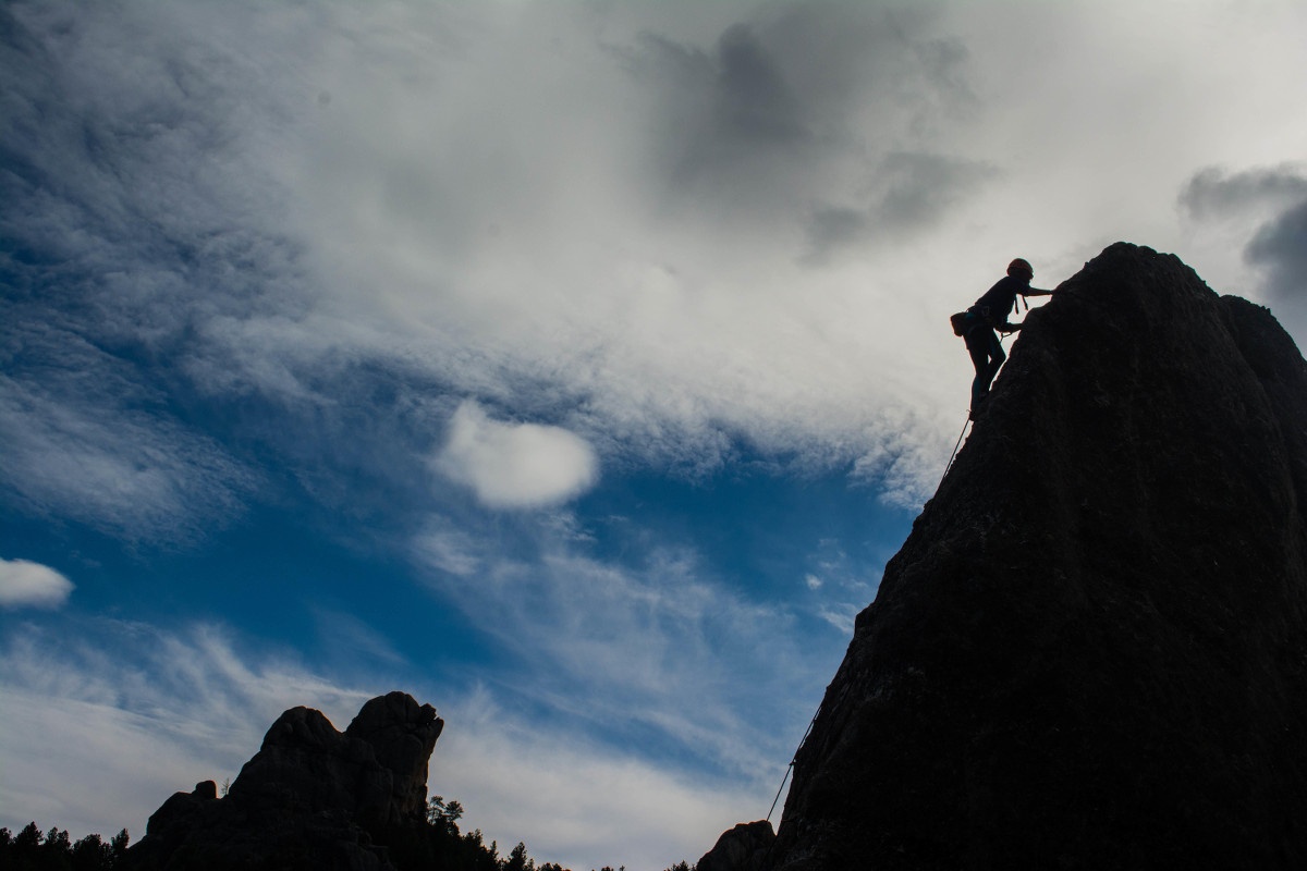 Silhouette of a rock climber ascending a rock dome