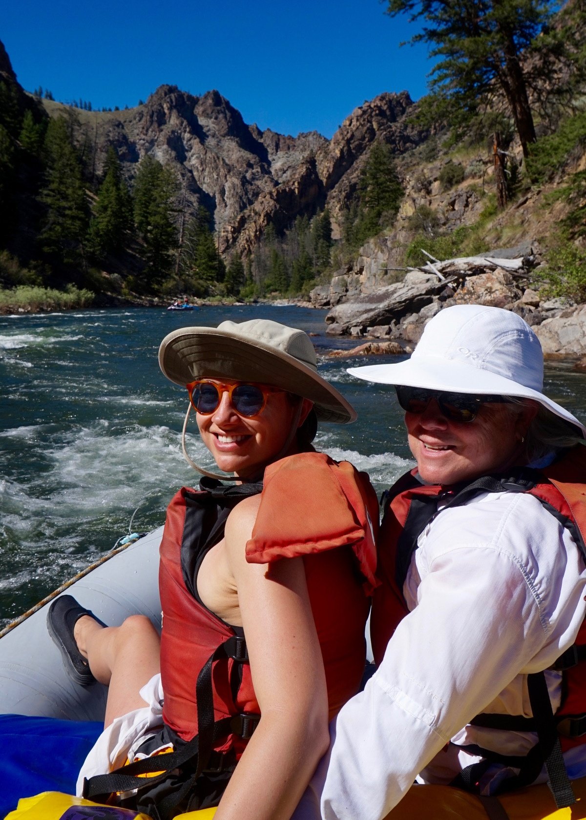 two smiling family members in close quarters sitting in a raft on the river