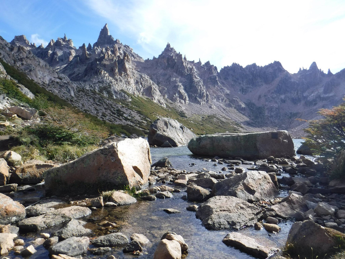 creek with large rocks in a mountain valley surrounded by jagged peaks