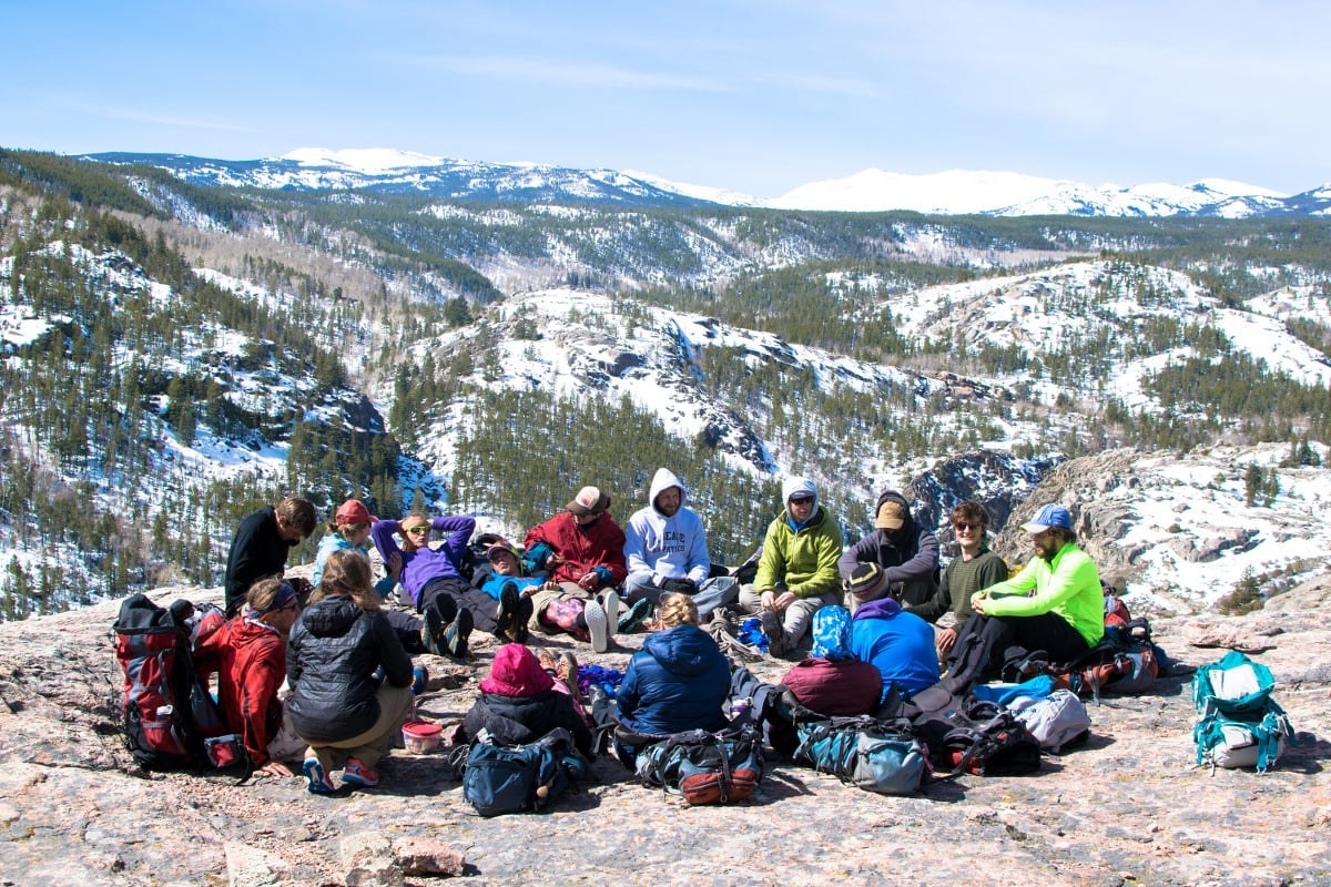 A group sits in a circle on a mountain ridge