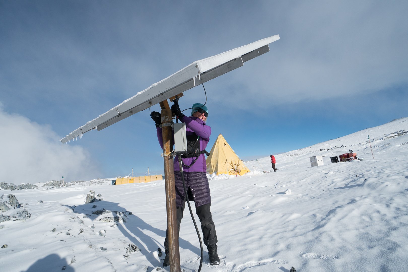 Woman repairs solar panel on snowfield