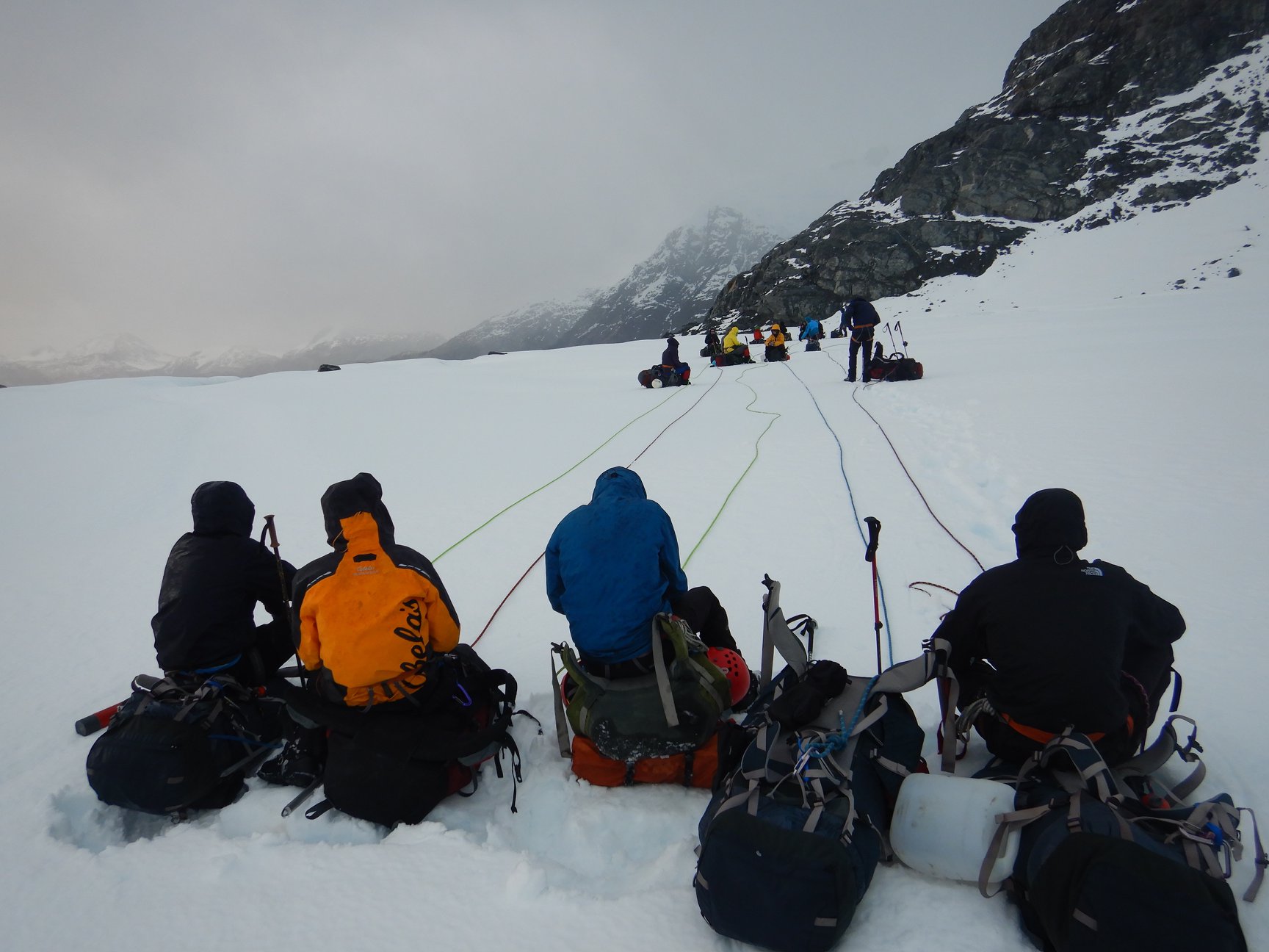 Four rope teams take a break on a glacier covered in snow