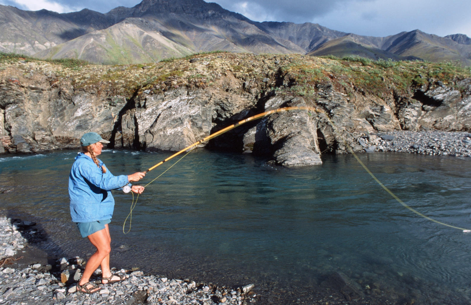 NOLS participant fishing on a rocky shore in Alaska