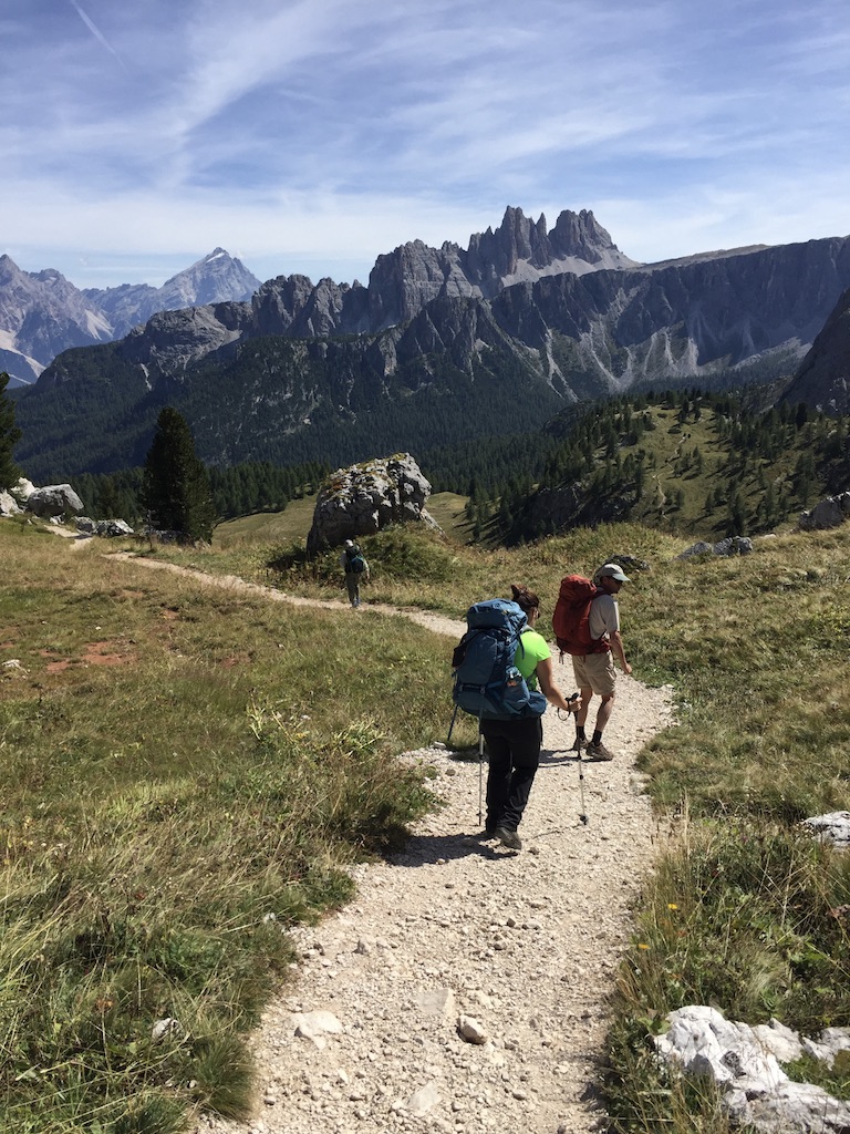 Group of hikers on trail in the mountains with craggy peaks behind