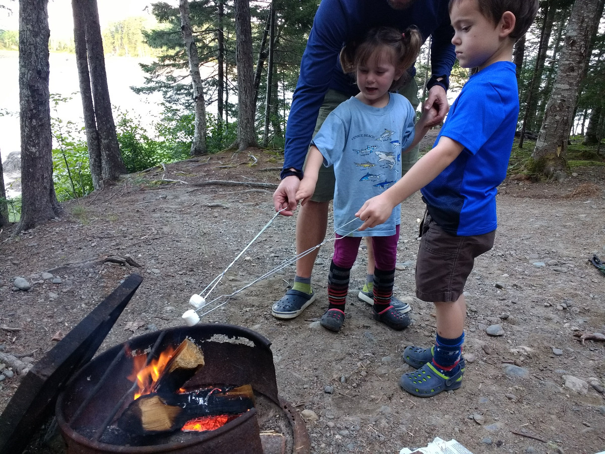 Kids roast marshmallows with help from parent