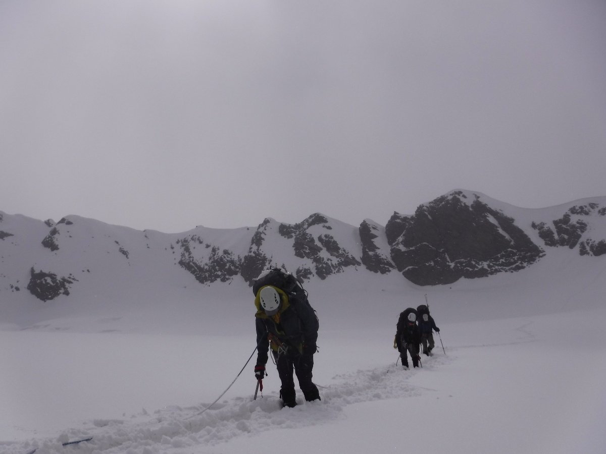 A rope team traveling through deep, heavy snow on a particularly difficult day on the Kafni Glacier