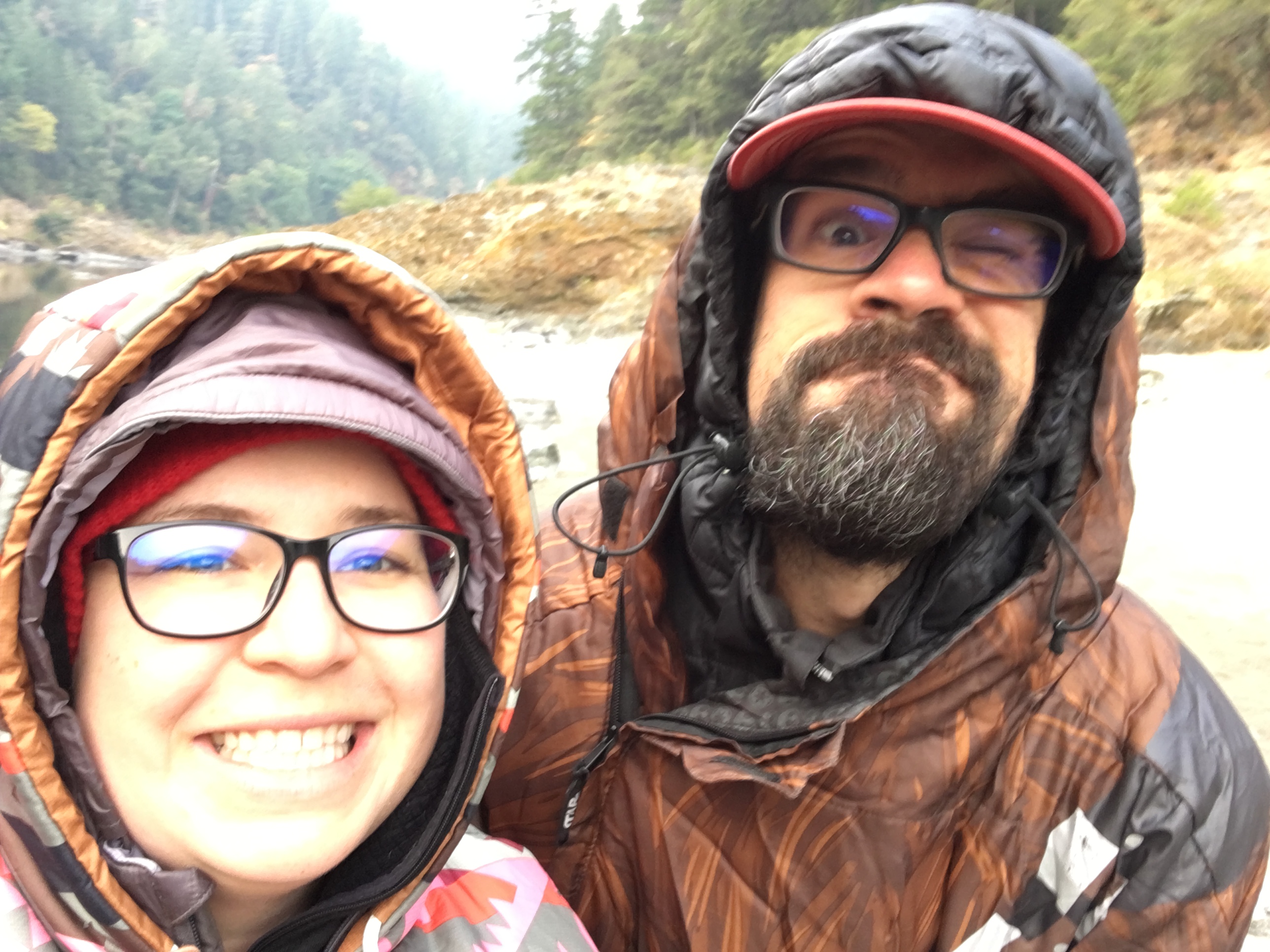 Ashely Drake and her husband smile while taking a selfie photo wearing rain gear
