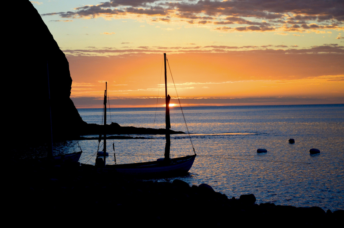 Sunrise photo of anchored longboat silhouette