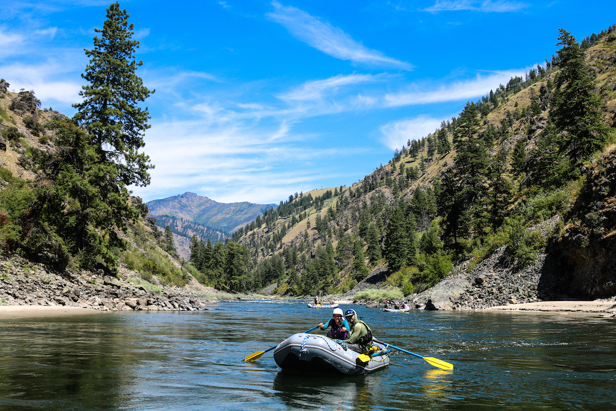 two NOLS participants paddle a raft on the Salmon River on a sunny day