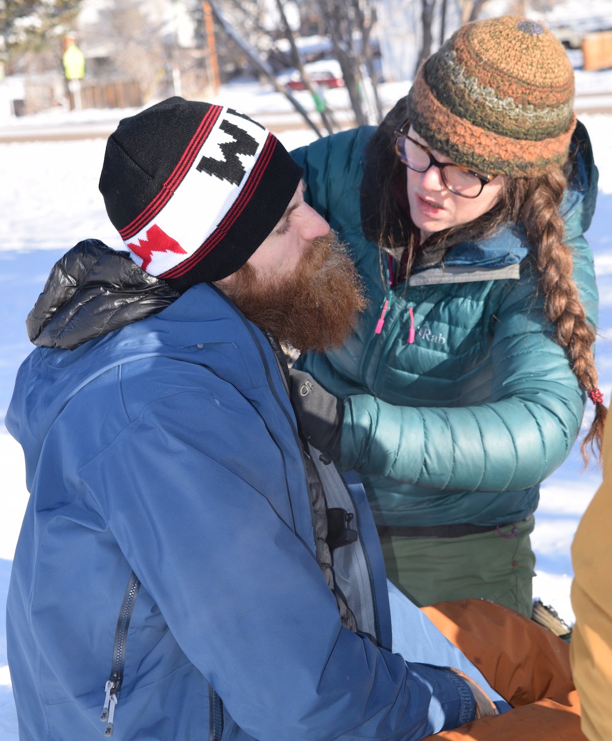 NOLS wilderness medicine students wearing winter gear practice taking a pulse