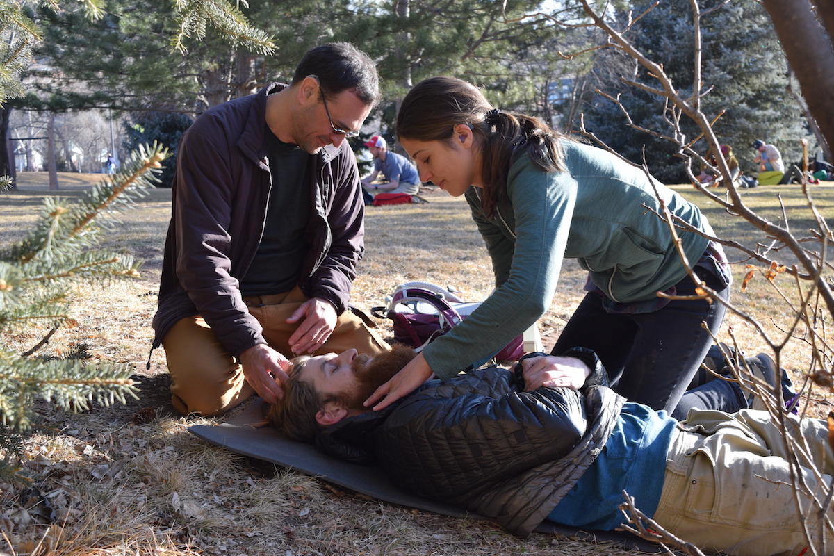 two NOLS Wilderness Medicine students practice caring for a patient with possible spine-injury mechanism