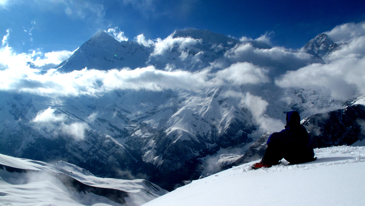 NOLS mountaineering student gazes at the snowy peaks of the Himalayas high in the clouds