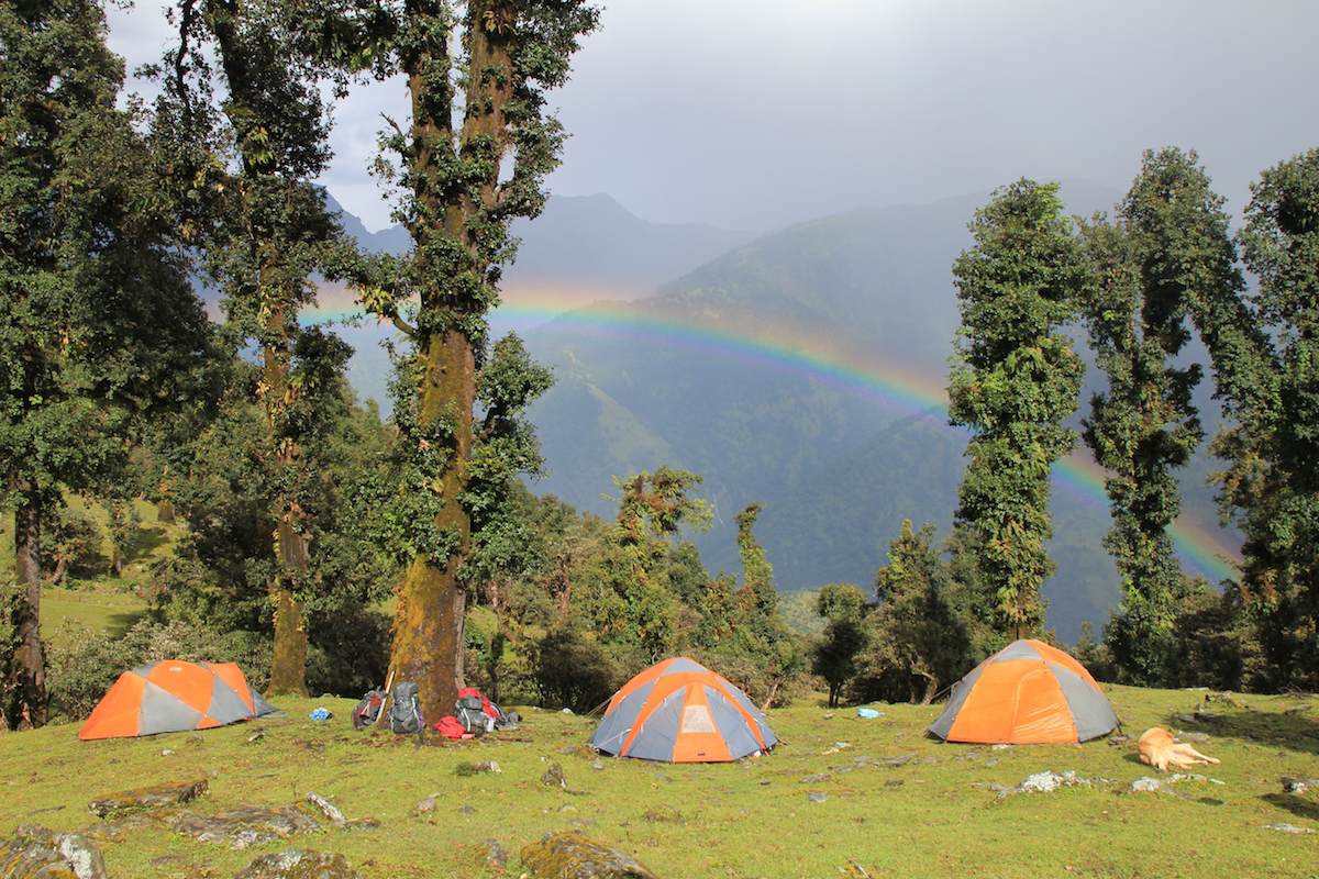 three NOLS tents in the Himalaya with a rainbow overhead