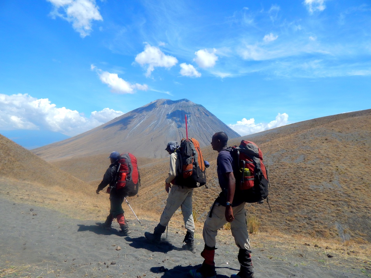 3 course participants trek with mountain in the background