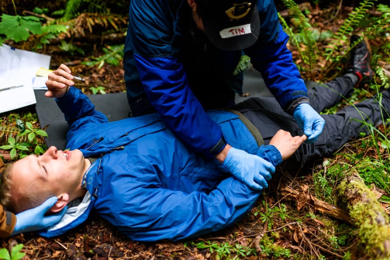 NOLS student practices patient assessment by checking patient's hand during a scenario on their course
