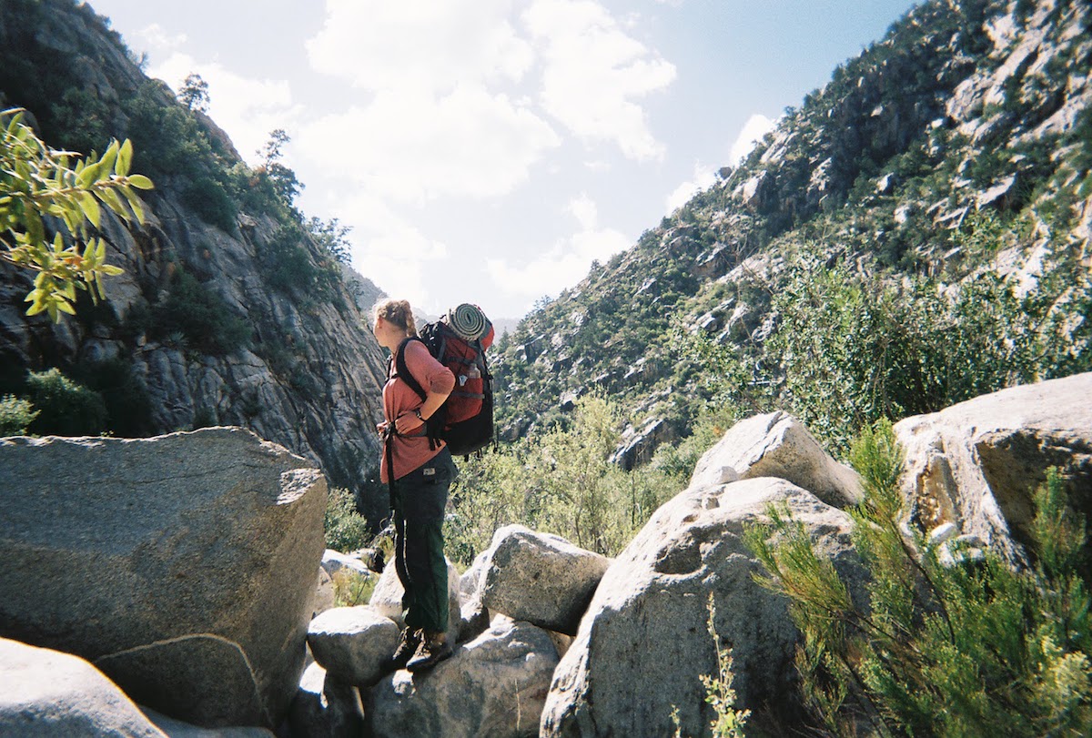 NOLS student stands on boulders while hiking in Baja California