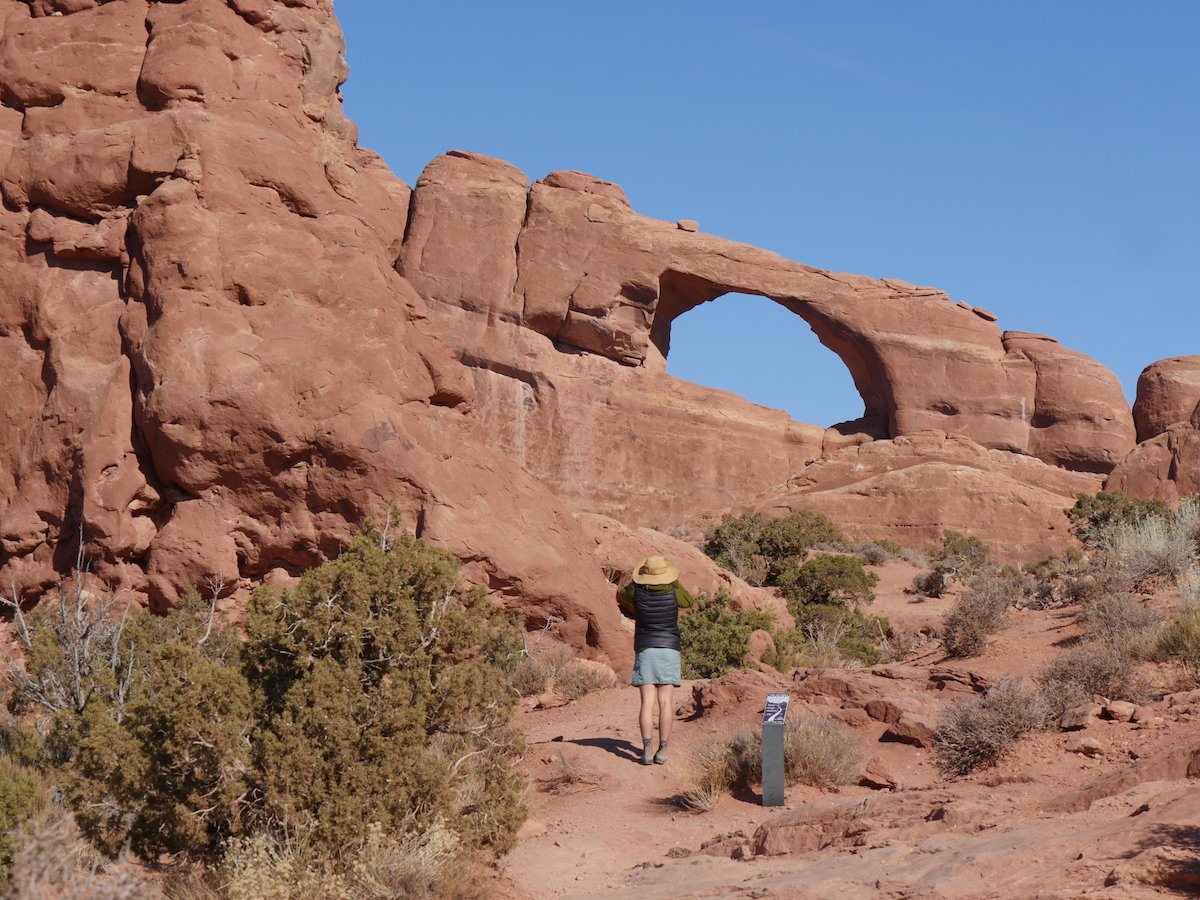 hiker wearing a hat explores Arches National Park